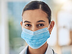 Young female mixed race nurse wearing a mask to protect herself from covid disease while working at a hospital. Portrait of a young female hispanic doctor standing at a clinic 