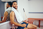 Young athlete sitting in a gym locker room. Mixed race athlete taking a break from his workout. Portrait of smiling fit man relaxing in his gym. Hispanic player resting after a match
