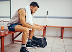 Serious young player sitting in a locker room. Mixed race man waiting in a gym locker room. Young man taking a break from his match, thinking in the gym. Focused man in the gym