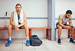 Portrait of a caucasian athlete sitting in a locker room. Two men sitting in a gym locker room together. Serious player relaxing in a gym together. Professional players resting together