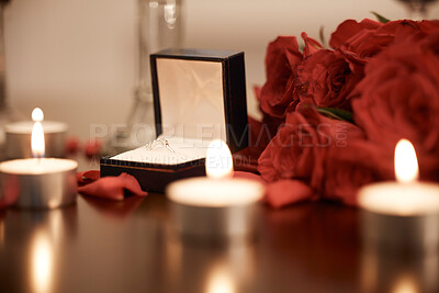Buy stock photo Closeup of romantic engagement ring box, fresh red roses and candles in an empty room at night. Getting ready and prepared for surprise proposal. Loving couple popping the question with sweet gesture