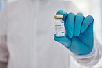 Hand of a doctor holding a vial of covid vaccine. Ready to cure the world of covid. Closeup on hands of a medical specialist holding cure to corona virus. Disease expert holding a vial of vaccine