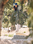 Young man showing his cycling skills while out cycling on a bicycle outside. Adrenaline junkie practicing a dirt jump outdoors. Male wearing a helmet doing extreme sports with a mountain bike
