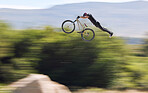 Young man showing his cycling skills while out cycling on a bicycle outside. Adrenaline junkie practicing a dirt jump outdoors. Male wearing a helmet doing extreme sports with a mountain bike