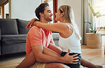 Happy caucasian couple being affectionate and enjoying romantic intimate moment while sitting on living room floor. Young woman sitting on top of boyfriend and putting her arms around him
