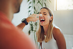 Close up of happy young caucasian couple having fun in the bathroom. Cheerful woman laughing as boyfriend playfully smears foam on her nose while washing his hands
