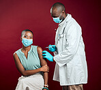 African american doctor giving covid vaccine to black woman wearing surgical face mask. Healthy patient getting corona injection from physician with needle against red studio background with copyspace