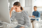 Young stressed mixed race businesswoman suffering from a headache while working on a desktop computer at work. One unhappy hispanic female businessperson suffering from anxiety while working on a computer at a desk in an office