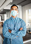 Young asian businessman standing with his arms crossed and wearing a mask at work. One confident chinese male boss wearing a mask protecting from a virus and standing at work