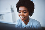 One happy young african american call centre telemarketing agent talking on a headset while working on computer in an office. Face of confident friendly female consultant operating helpdesk for customer service and sales support