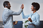 Two happy african american call centre telemarketing agents giving each other a high five and cheering with joy while drinking coffee in an office. Excited and ambitious consultants celebrating successful sales targets and winning victory