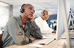 Stressed african american call centre telemarketing agent looking bored and anxious while working on broken computer in an office. Worried female consultant having problems with slow internet connection error. Lazy employee struggling difficult callers