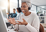 Happy african american call centre telemarketing agent talking on a headset while working on a computer in an office. Confident friendly female consultant operating a helpdesk for customer service and sales support