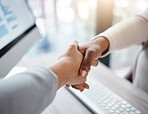 Closeup of two businesswomen shaking hands over a desk during a meeting in an office. Colleagues finalising a successful promotion, deal and merger. Coworkers greeting while collaborating and negotiating during job interview
