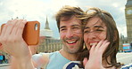 Young couple waving during a video call made using a cellphone on holiday