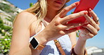 Closeup of a woman using her smartphone to send a text during her vacation