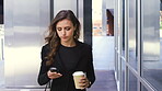 young businesswoman drinking coffee while using her cellphone. Young caucasian businesswoman drinking tea and using her smartphone while walking in the city
