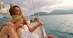 Two happy friends hugging and laughing during a cruise. Two cheerful women laughing on a yacht cruise on the ocean. Cheerful friends laughing and hugging each other during a cruise on a cloudy day.