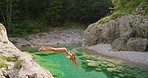 Woman in white bikini diving into a lake to swim on holiday. Woman on holiday swimming in a lake after jumping from a cliff. Woman in white bikini swimming in a lake