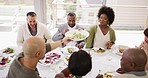 Diverse group of cheerful best friends from above eating and drinking wine while having lunch party around a table in a restaurant or home. Happy men and women socializing with each other over a meal