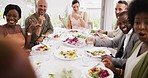 Diverse group laughing at a party enjoying their food and wine. People eating and drinking alcohol, socializing together at a large dinner table. Friends having lunch in a dining room at home